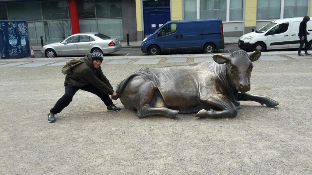 Homem segurando o rabo de um touro de metal simbolizando coragem para sair do Brasil e morar no exterior